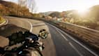 Ein Motorrad fährt auf einer Strasse bei tiefstehender Sonne