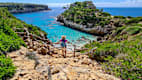 Eine Frau genießt den Ausblick auf die Bucht Cala des Moro auf Mallorca