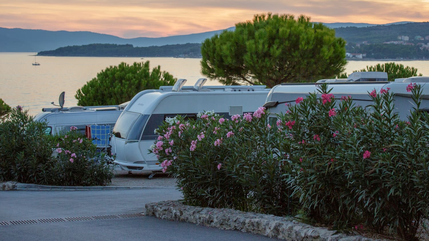 Ausblick aufs Meer und im Vordergrund mehrere Wohnmobile und Pflanzen