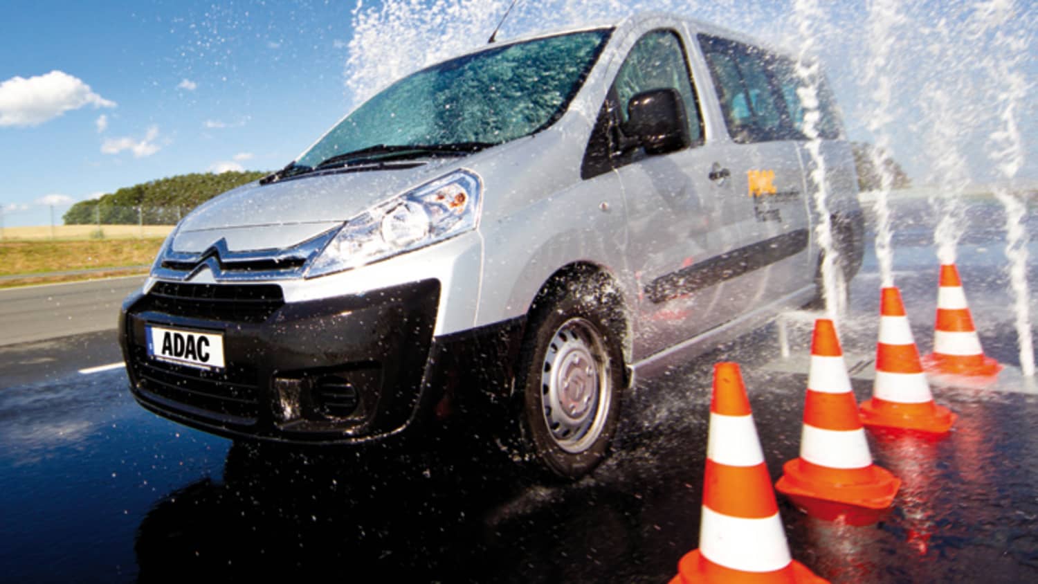 Citroen Kleintransporter fährt neben Pylonen durch Wasserfontäne bei ADAC Fahrsicherheitstraining