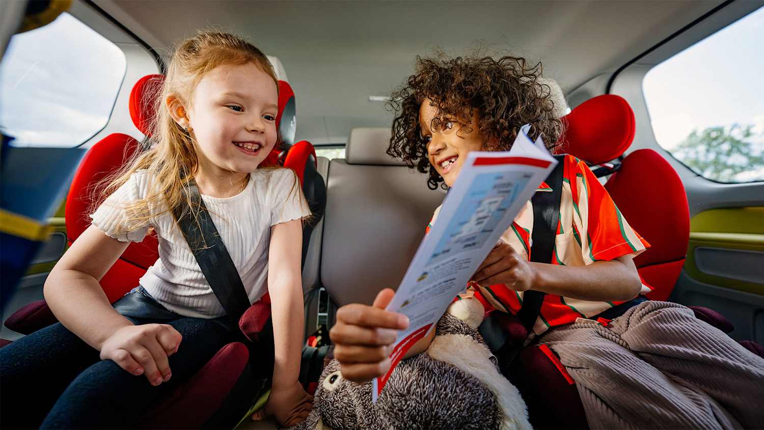 Zwei Kinder auf der Rückbank eines Autos vertreiben sich die Zeit mit einem Spiel.