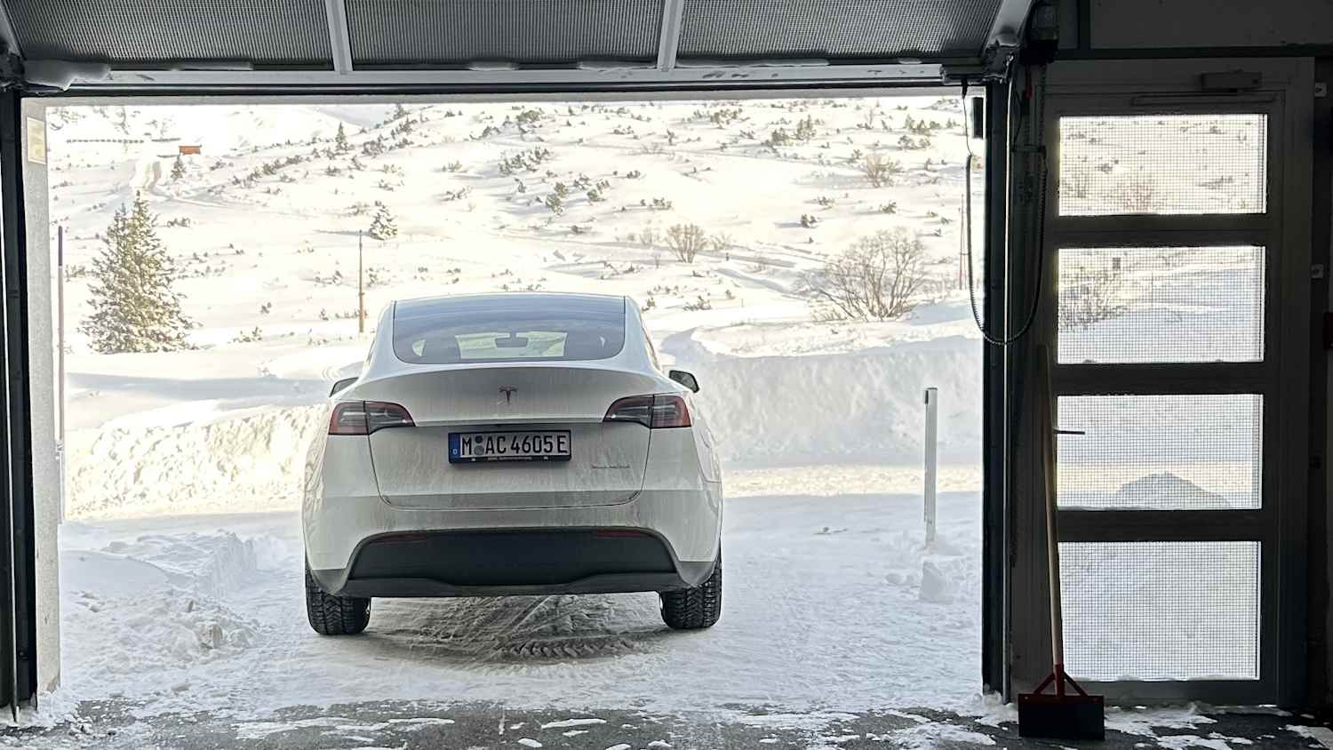 Tesla Model Y vor der am Tor der Hotelgarage in der Winterlandschaft von Obertauern  