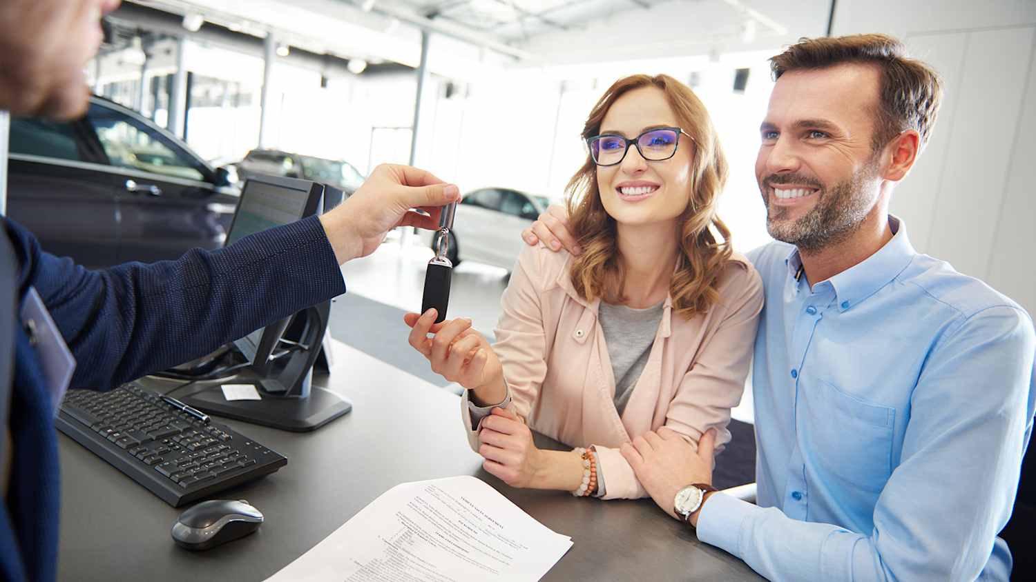 Pärchen sitzt im Autohaus und bekommt den Autoschlüssel