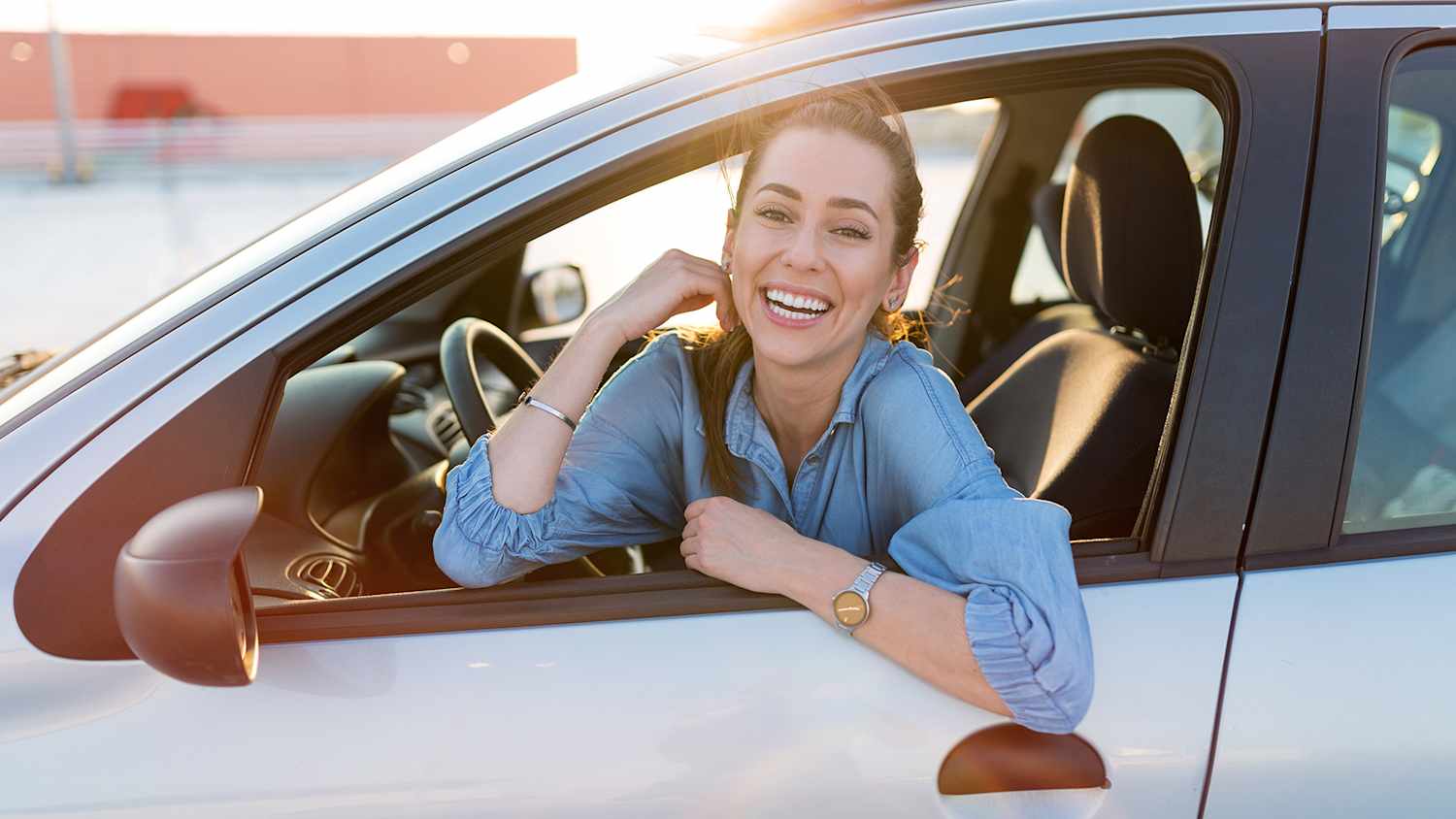 Frau lehnt sich aus dem offenen Fenster ihres Autos