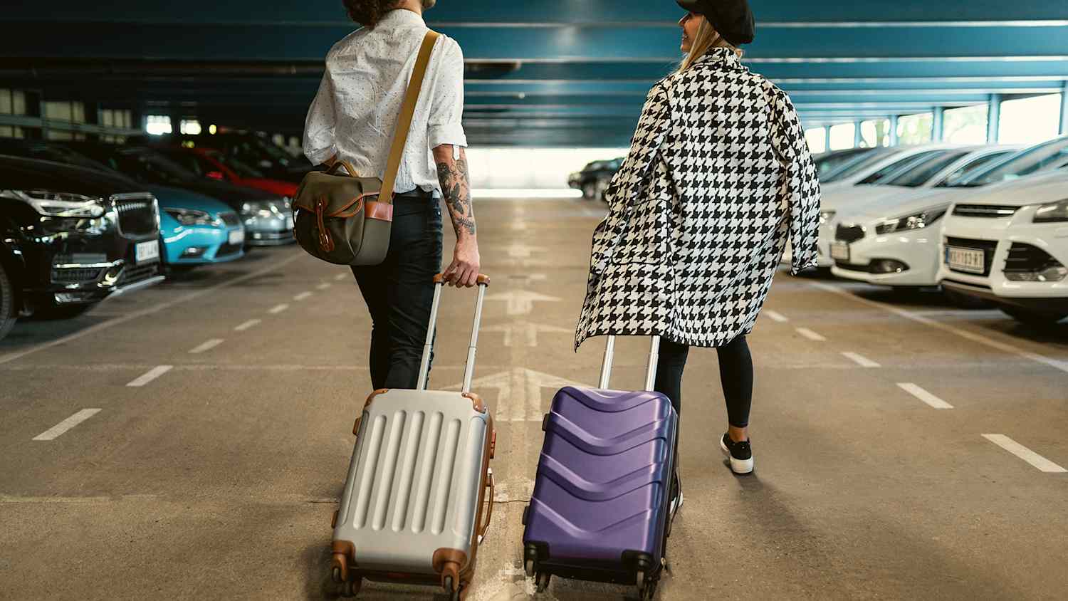 Pärchen geht in Parkhaus zu Mietwagen, nachdem sie die Mietwagenpreise verschiedener Anbieter verglichen hatten