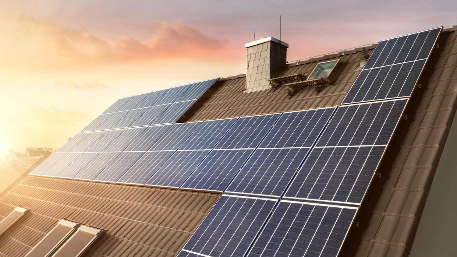 Solaranlage auf einem Hausdach bei Sonnenaufgang.
