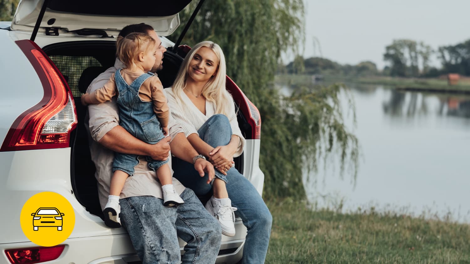Ein Mann, eine Frau und ein Kind sitzen im Kofferraum eines weißen Autos an einem See und halten das Familien-Leasingauto geflegt