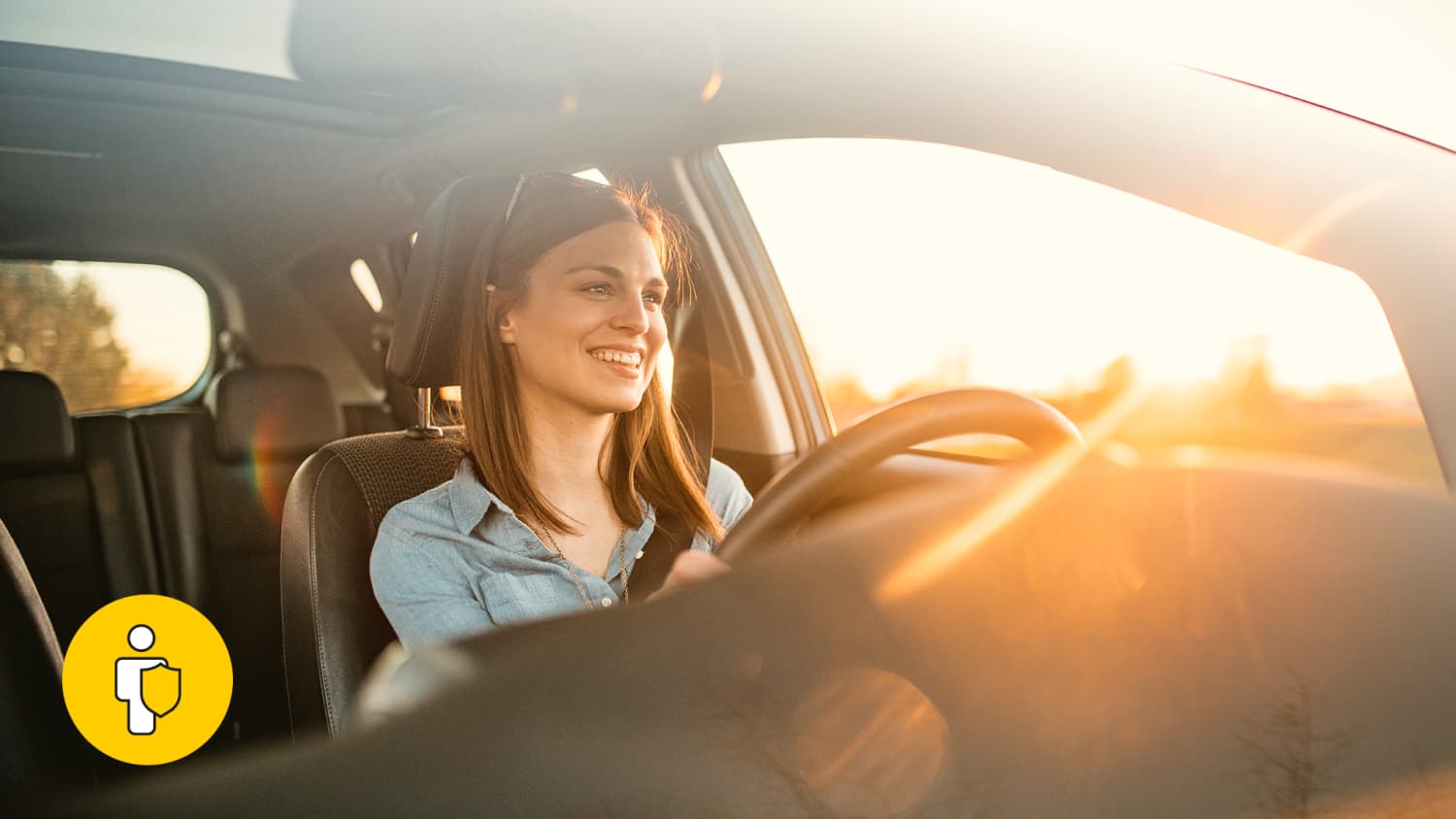 Frau sitzt hinter dem Steuer eines Autos bei Sonnenuntergang und lächelt, weil sie durch die GAP-Versicherung beim Leasing total abgesichert ist.