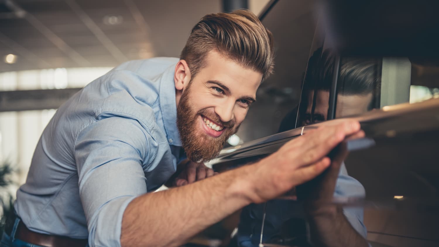 Mann streicht lächelnd an schwarzem Auto entlang, weil er leasing Tipps erhalten hat