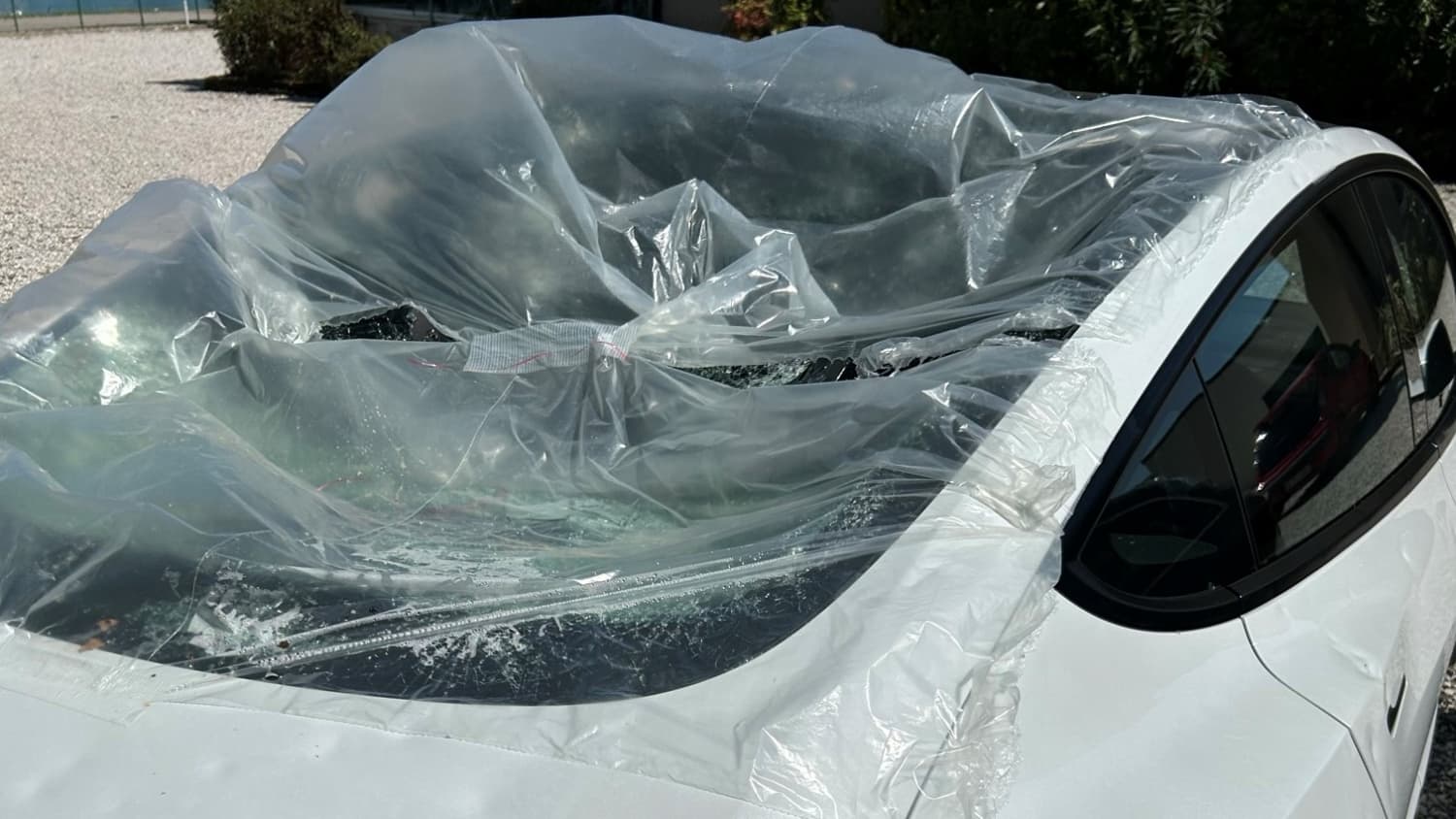 Ein weißer Tesla mit einem Dachschaden, der Auswirkungen auf den Beitrag der Autoversicherung haben kann