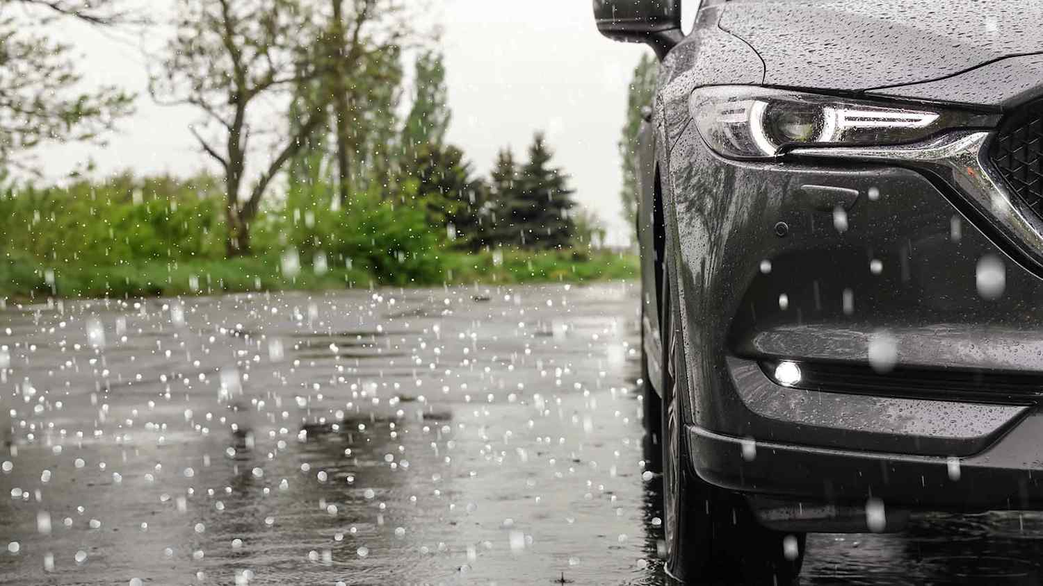 Hagelkörner prasseln auf Straße und Auto und können Hagelschäden verursachen