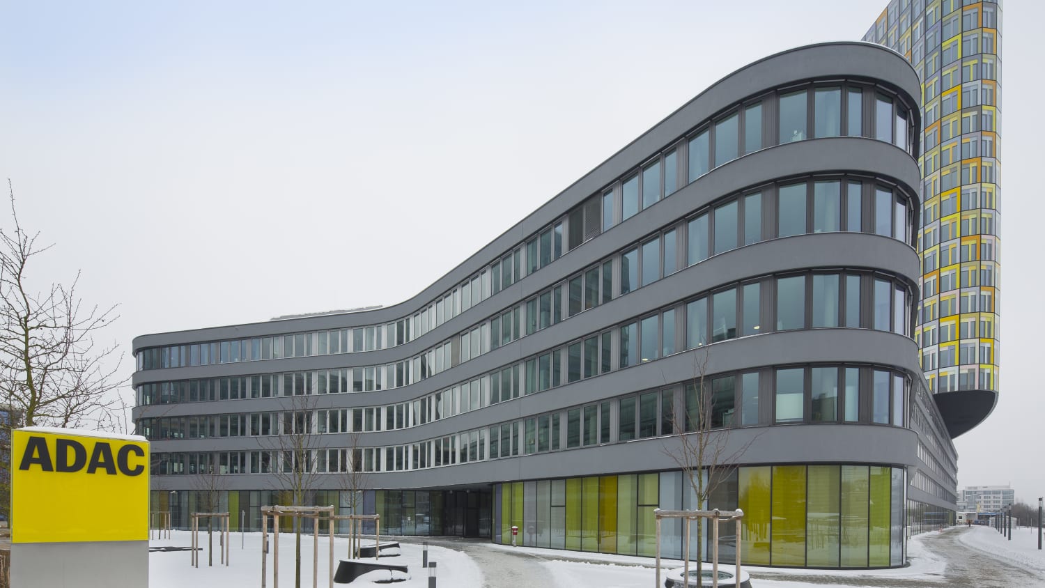 ADAC Zentrale von der Seite mit ADAC Logo im Vordergrund und verschneitem Gelände