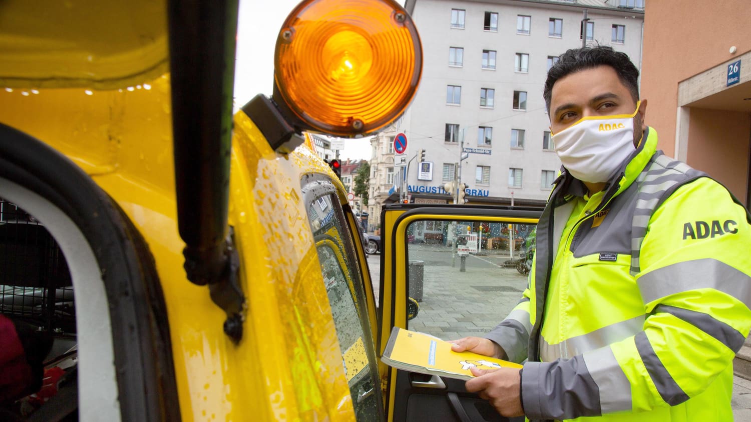 Ein Pannenhelfer mit Corona-Maske steht neben seinem Auto