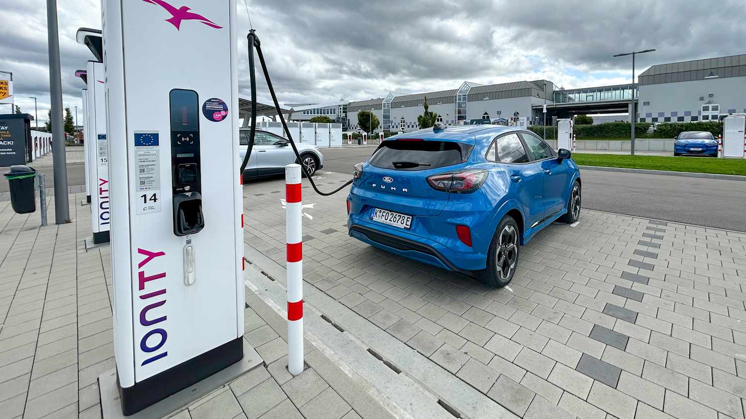 Blauer Ford Puma Gen-E an einer Ladesäule angeschlossen.