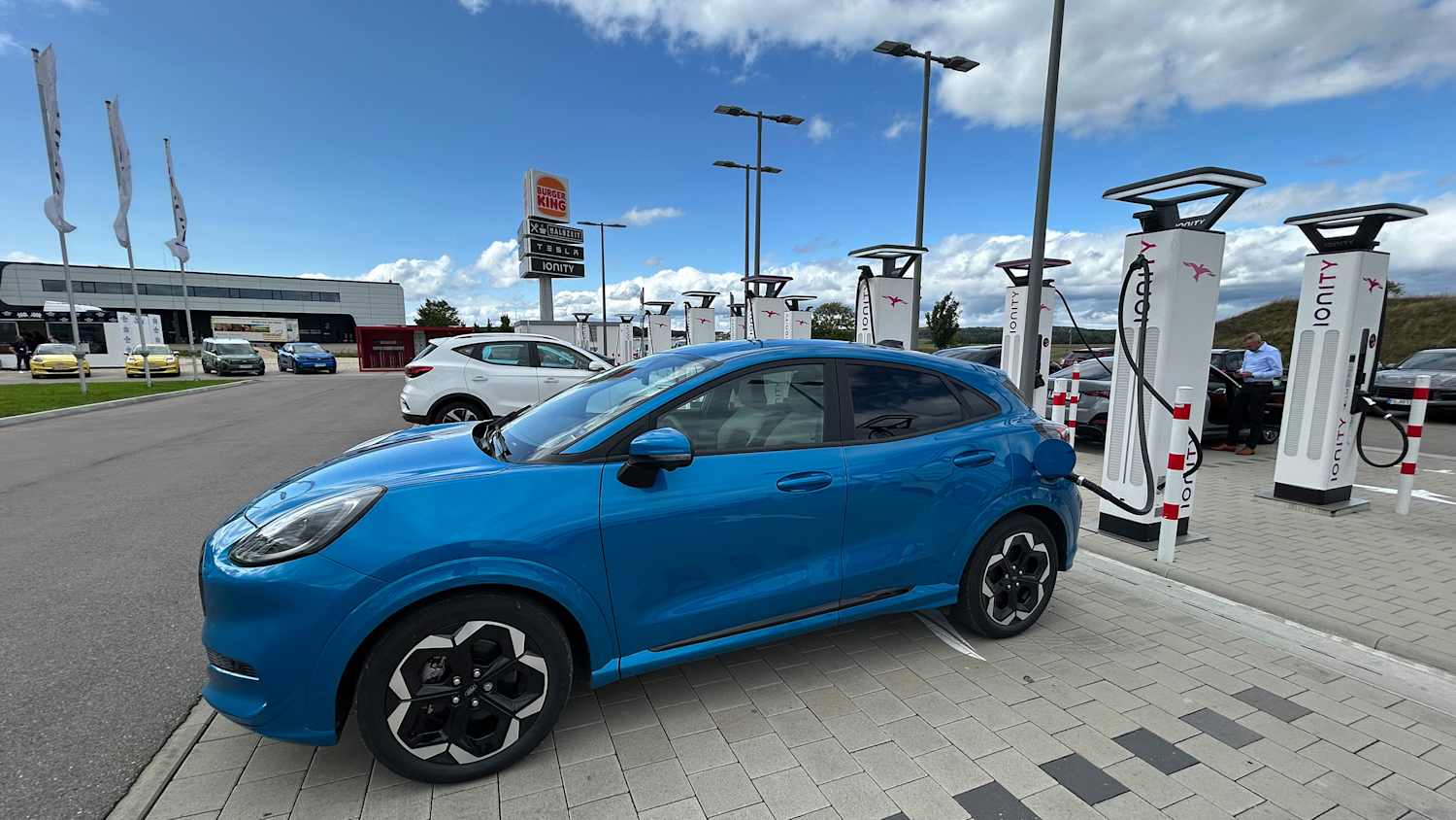 Blauer Ford Puma Gen-E an einer Ladesäule angeschlossen.