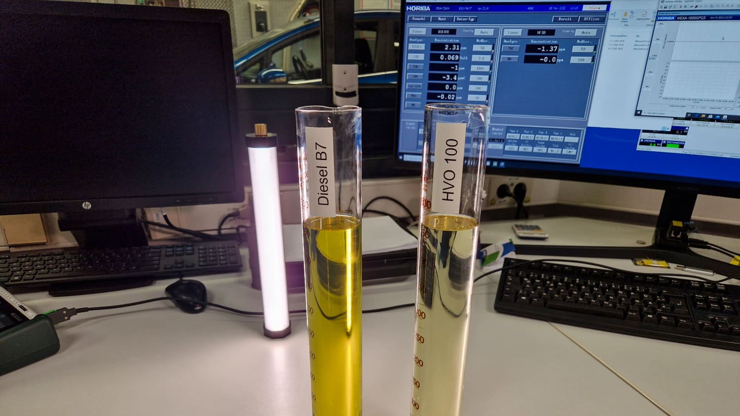 Ein Reagenzglas gefüllt mit Diesel steht neben einem Reagenzglass mit HVO Diesel auf einem Schreibtisch