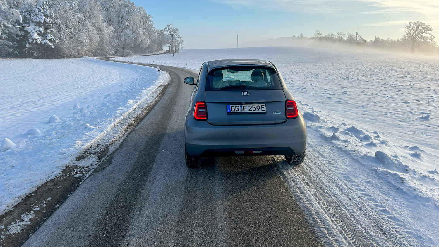 Heckansicht eines Fiat 500 der auf einer Straße in einer winterlichen Landschaft steht