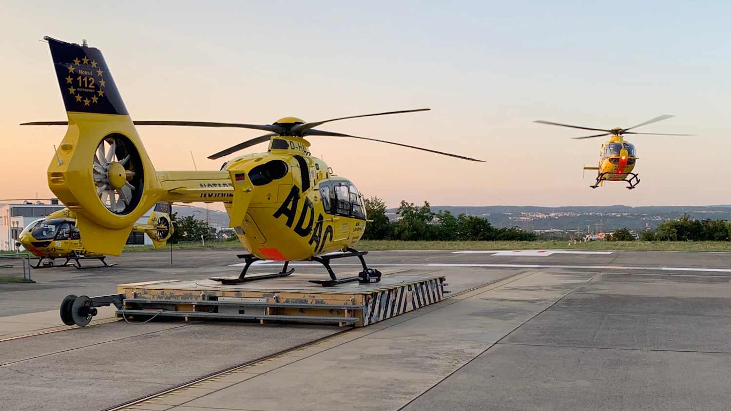 Ein ADAC Helikopter steht am Boden, ein Zweiter startet
