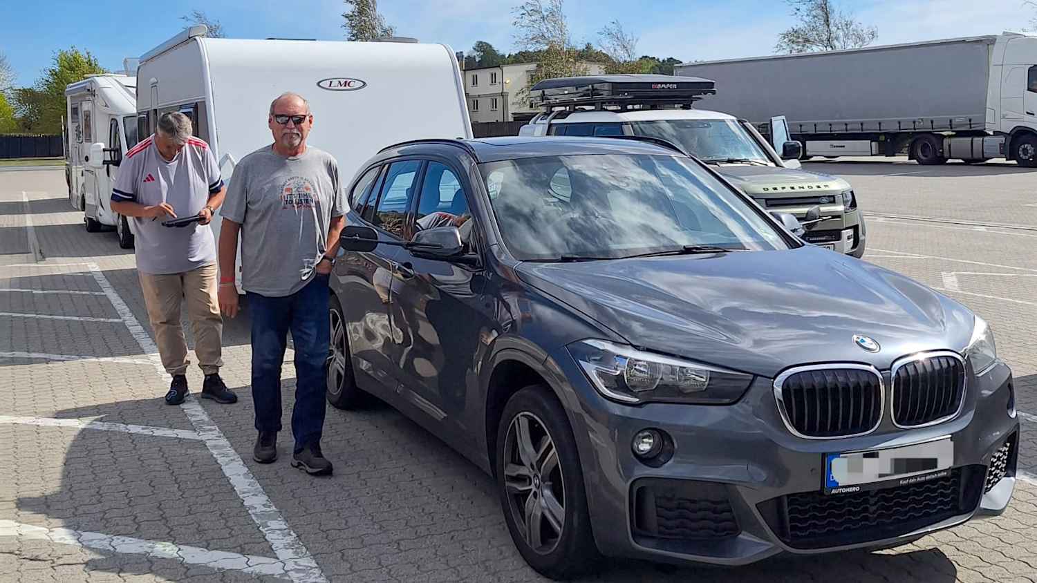 Zwei Männer stehen neben einem Auto mit Wohnmobil