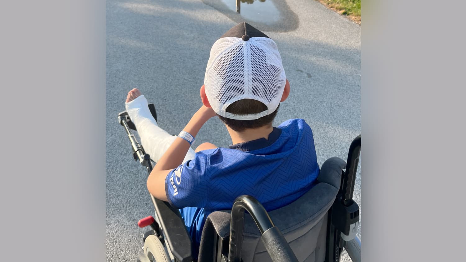 Ein Junge sitzt nach einem Sturz mit einem Gips-Bein im Rollstuhl