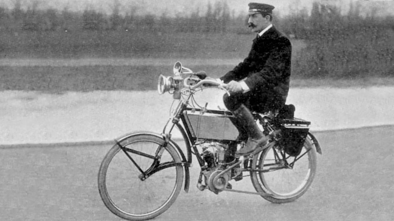 Historische Aufnahmen eines Mannes, der ein Motorrad fährt, dass aussieht, wie ein Fahrrad