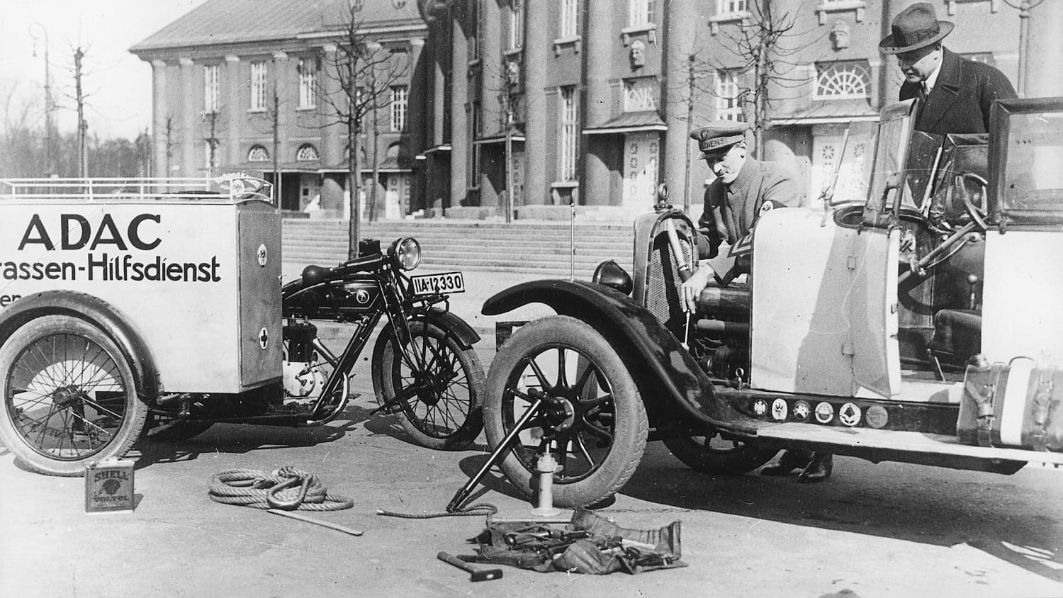 Strassenhilfsdienst repariert ein Auto in den 20ern.