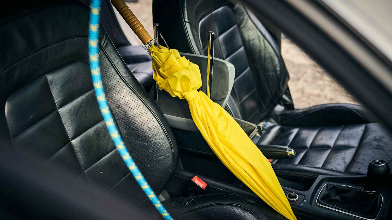 Ein gelber Regenschirm lehnt auf dem Beifahrersitz eines Autos