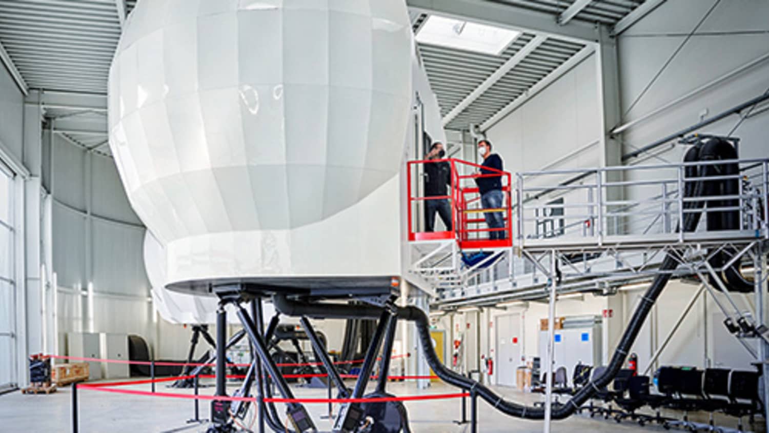 Hubschraubersimulator von außen, zwei Männer daneben