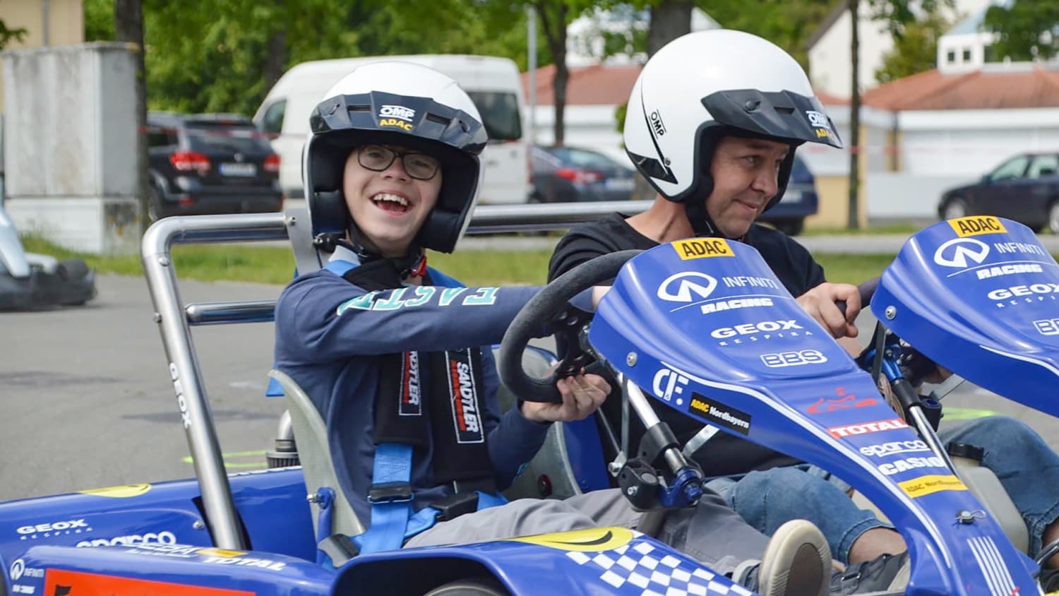 Ein Junge hat große Freude bei einer Fahrt mit Kurt Lada im eigens konstruierten Doppelsitzer-Kart