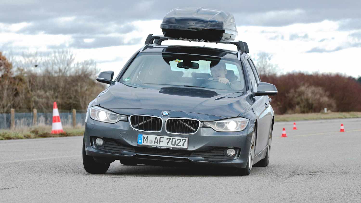 ein BMW mit einer Dachbox fährt scharfe Kurven und bremst stark ab um zu testen wie die Box hält