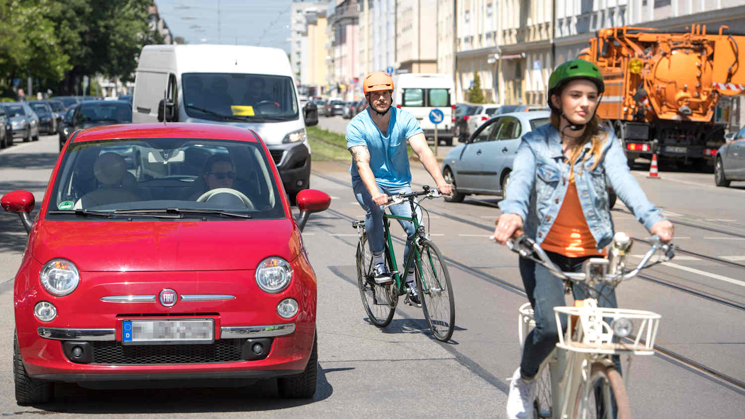 Zwei Fahrradfahrer und Autos im Münchner Straßenverkehr