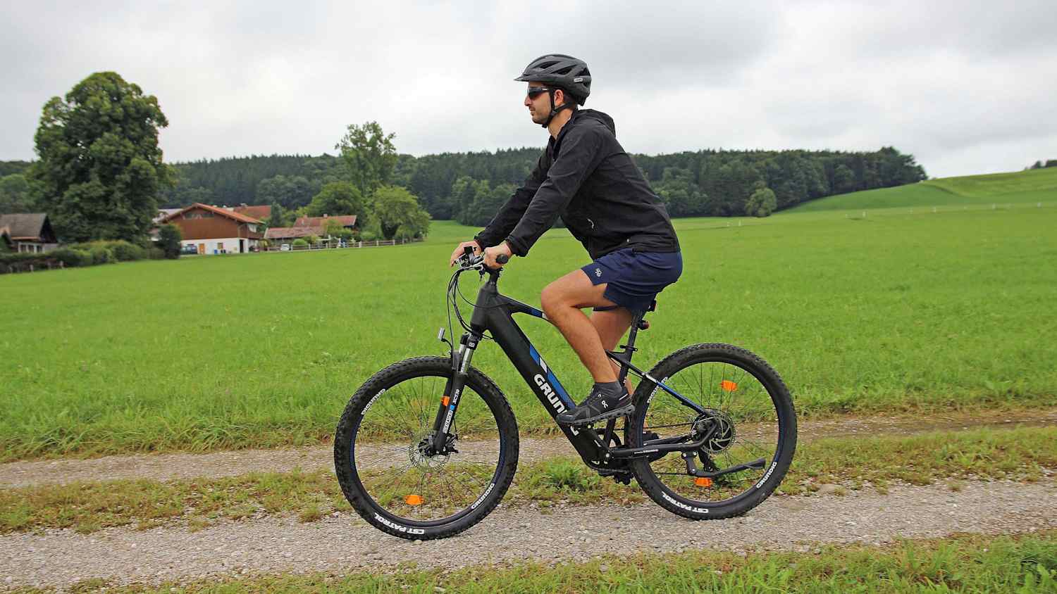 Ein Mann fährt auf einem Grundig E275 E-Bike auf einem Feldweg