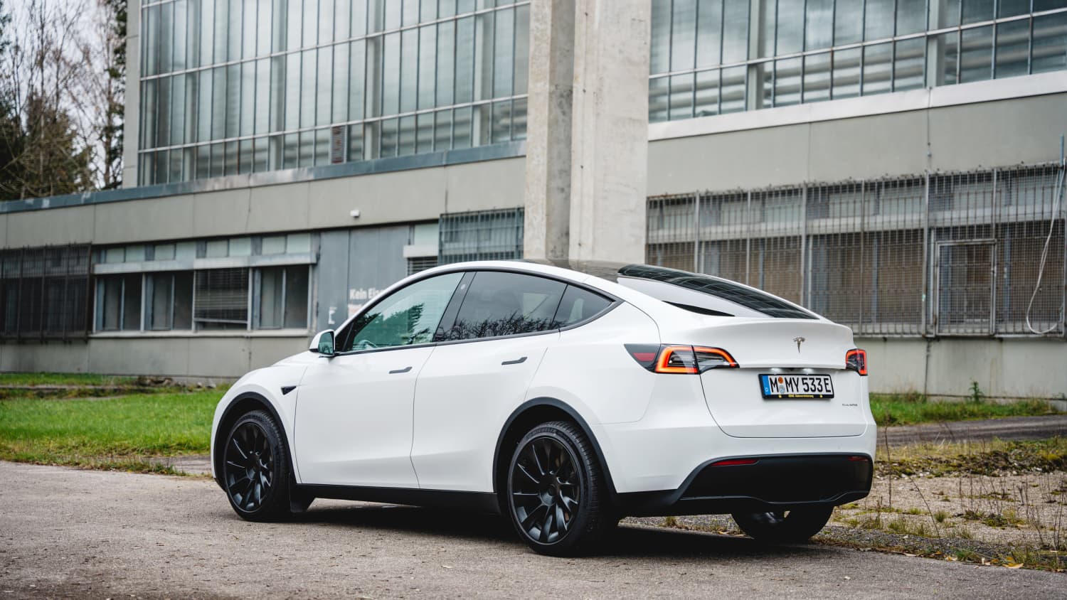 Weisses Elektro-SUV Tesla Model Y seitlich von hinten fotografiert