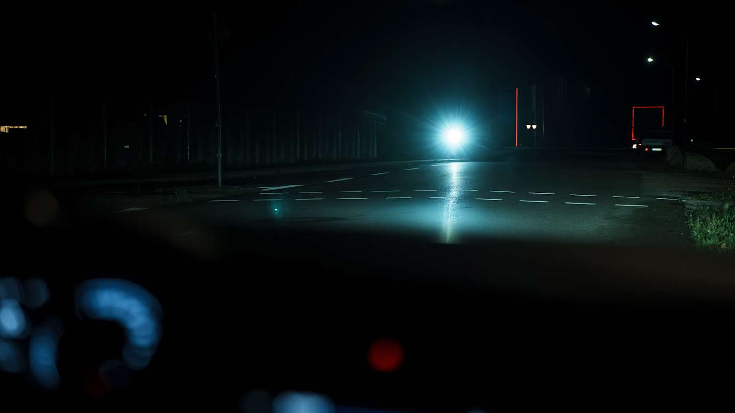 Blick aus dem Auto bei NAcht, ein Fahrradfahrer mit Scheinwerfer kommt entgegen