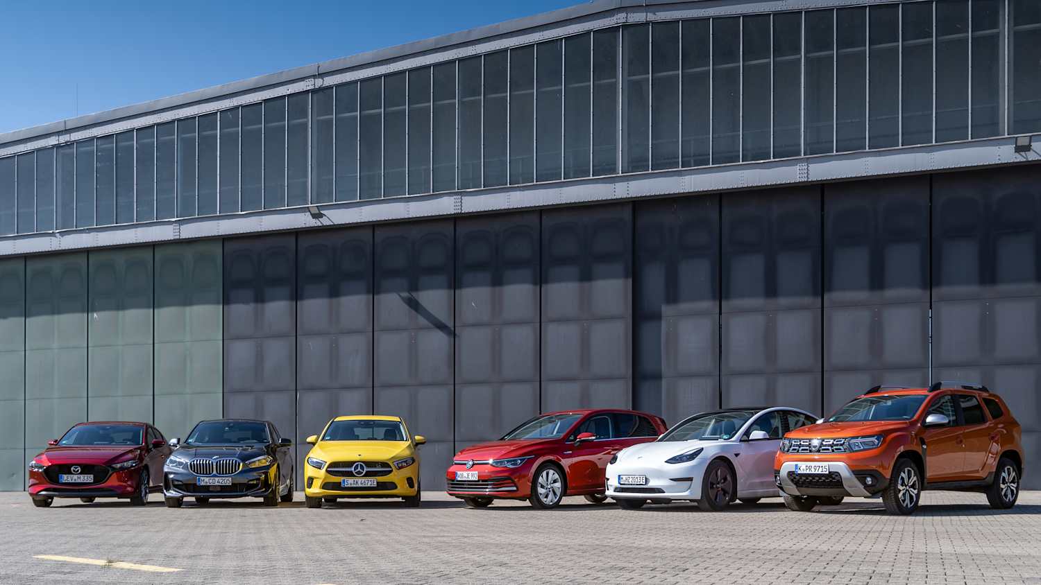 Ein Mazda 3, ein 1er BMW, eine Mercedes A-Klasse, ein VW Golf, ein Tesla Model 3 und ein Dacia Duster stehen nebeneinander