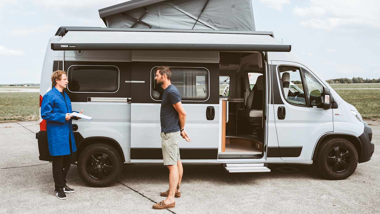 Zwei Menschen die sich vor einem Camper unterhalten