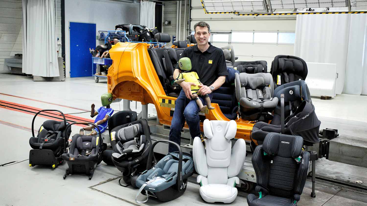 ADAC Testleiter Andreas Ratzek mit einem Kinderdummy und Kindersitzen beim ADAC Kindersitztest