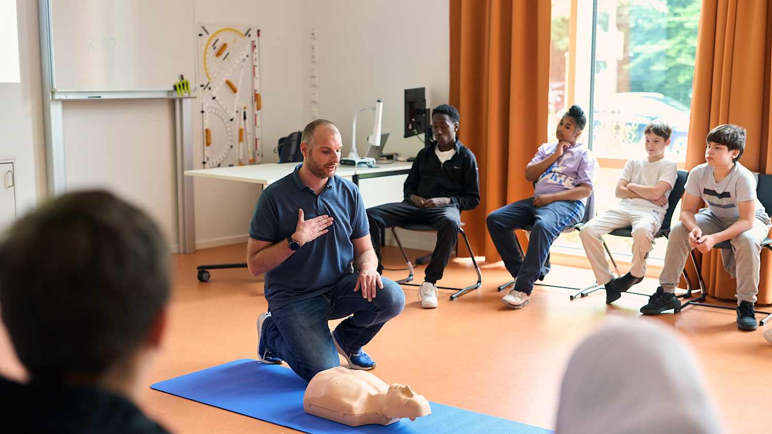 Ein Lehrer zeigt Teilnehmern, wo sie im Notfall drücken müssen
