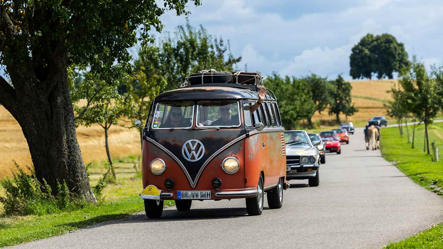 Eine Gruppe von Oldtimern fährt auf einer Landstraße