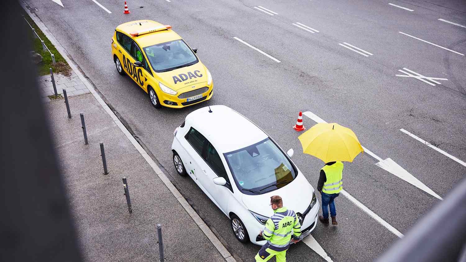 Ein ADAC Straßenwachtfahrer hilft einem Elektroautofahrer bei einer Autopanne