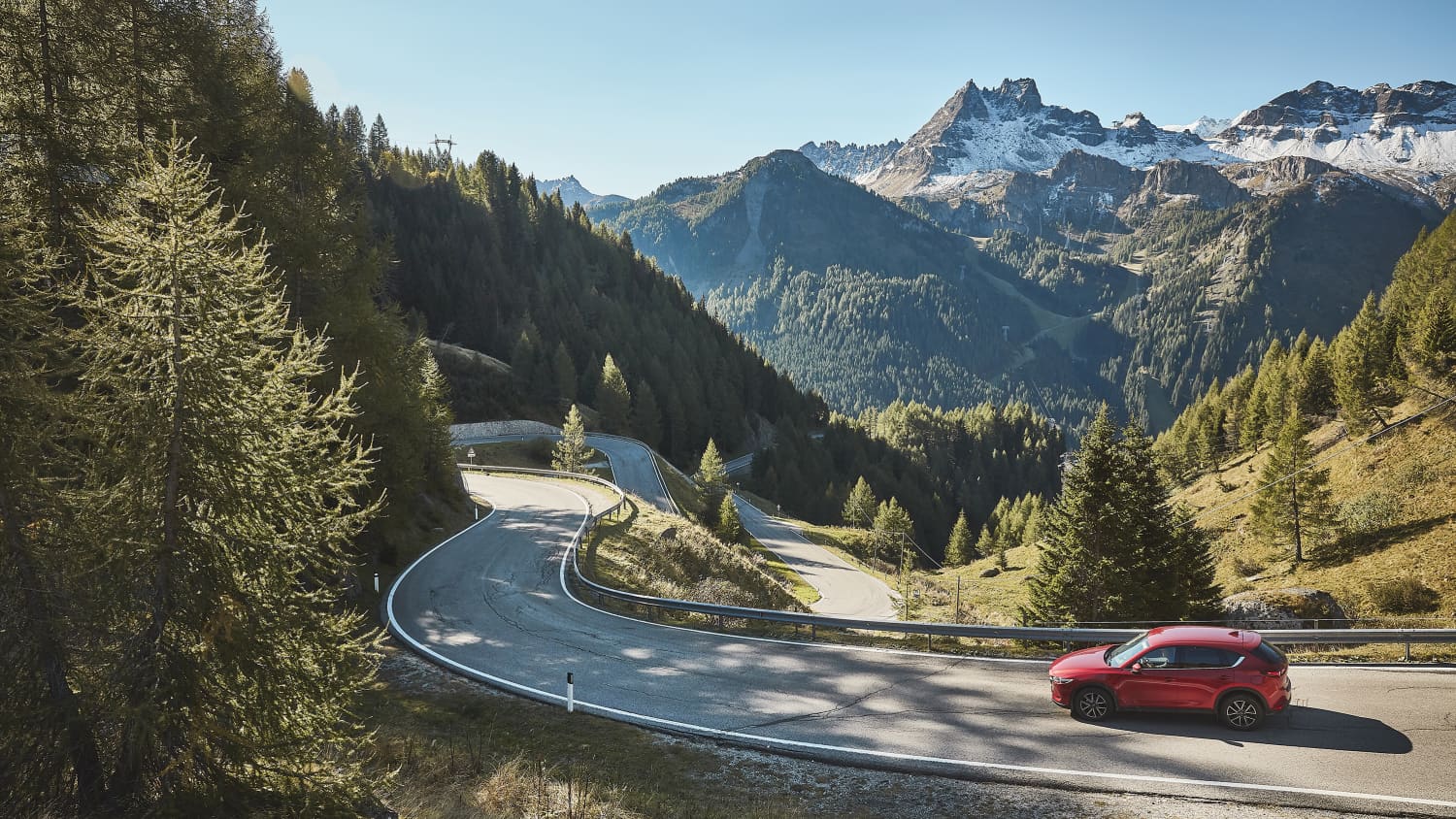 Ein rotes Auto fährt auf einer Passstrasse