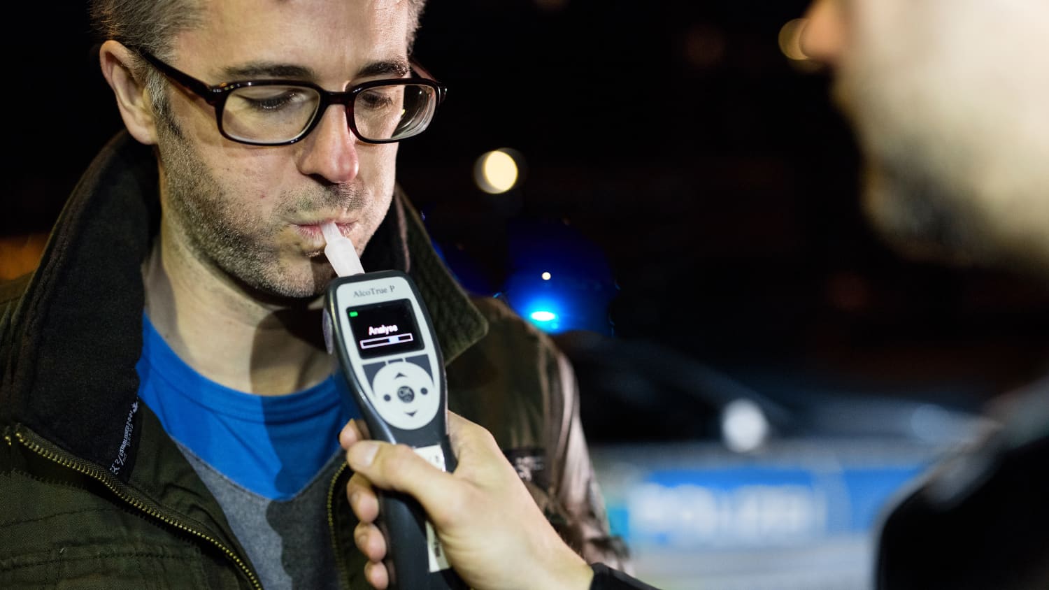 Ein Mann muss vor der Polizei ins den Alkoholomat pusten