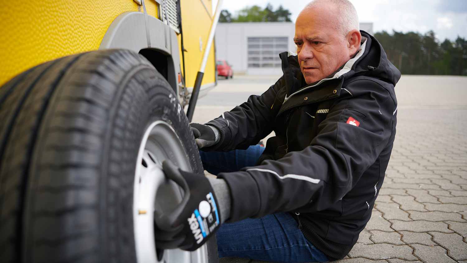 ADAC Campingexperte Martin Zöllner beim Reifenwechsel an einem Wohnwagen