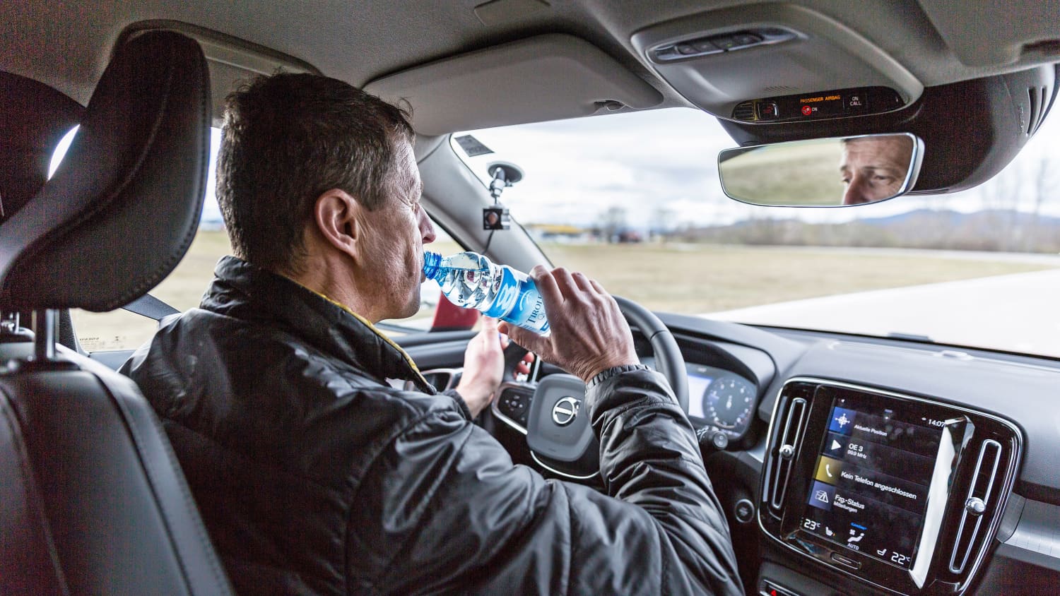 Ein Mann trinkt am Steuer eines Autos Wasser