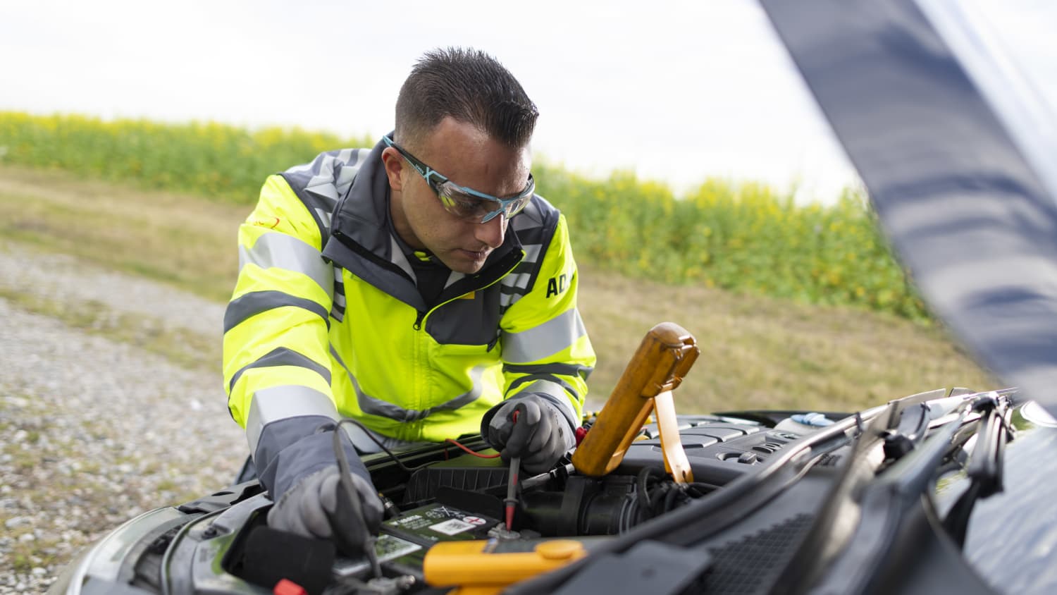 Ein ADAC-Pannenhelfer prüft die Spannung einer Autobatterie