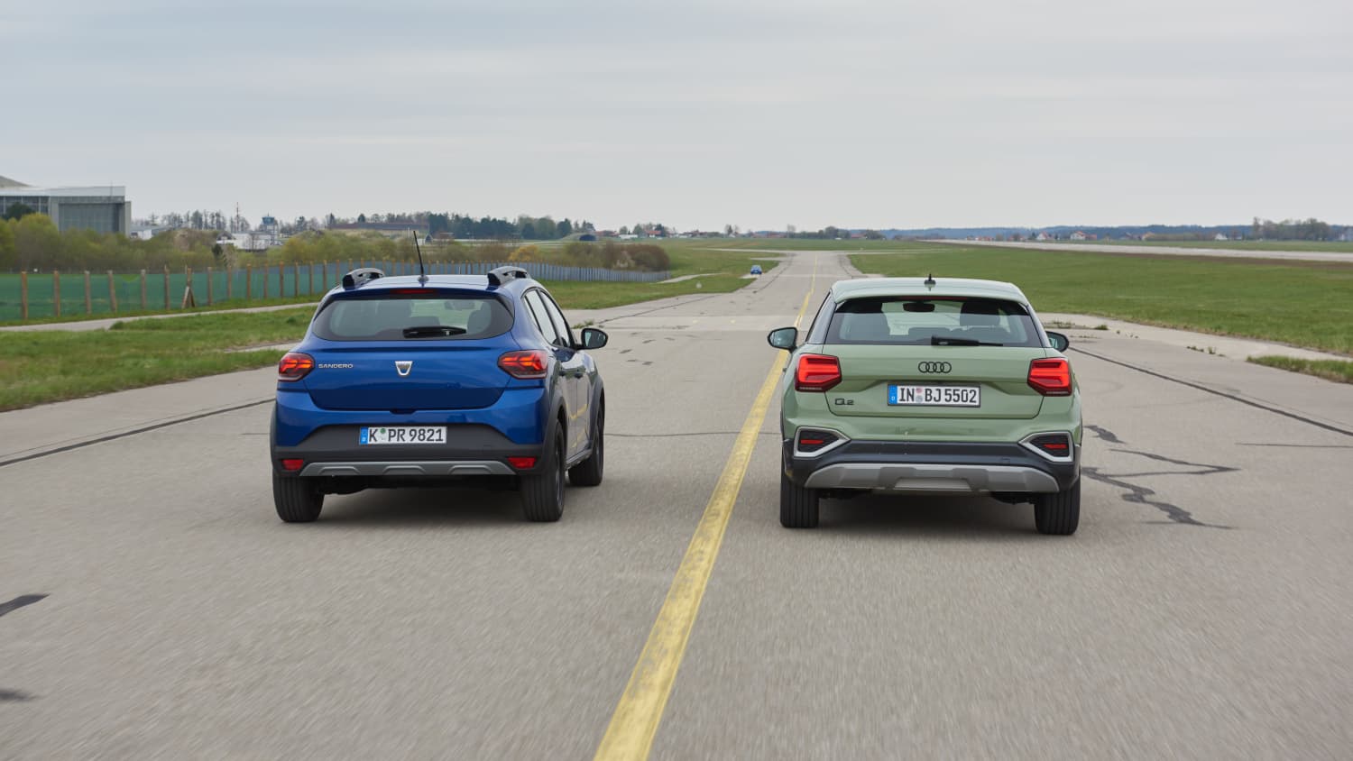 Vergleichstest vom Audi Q2 und Dacia Sandero, beide Autos von hinten nebeneinander fahrend.