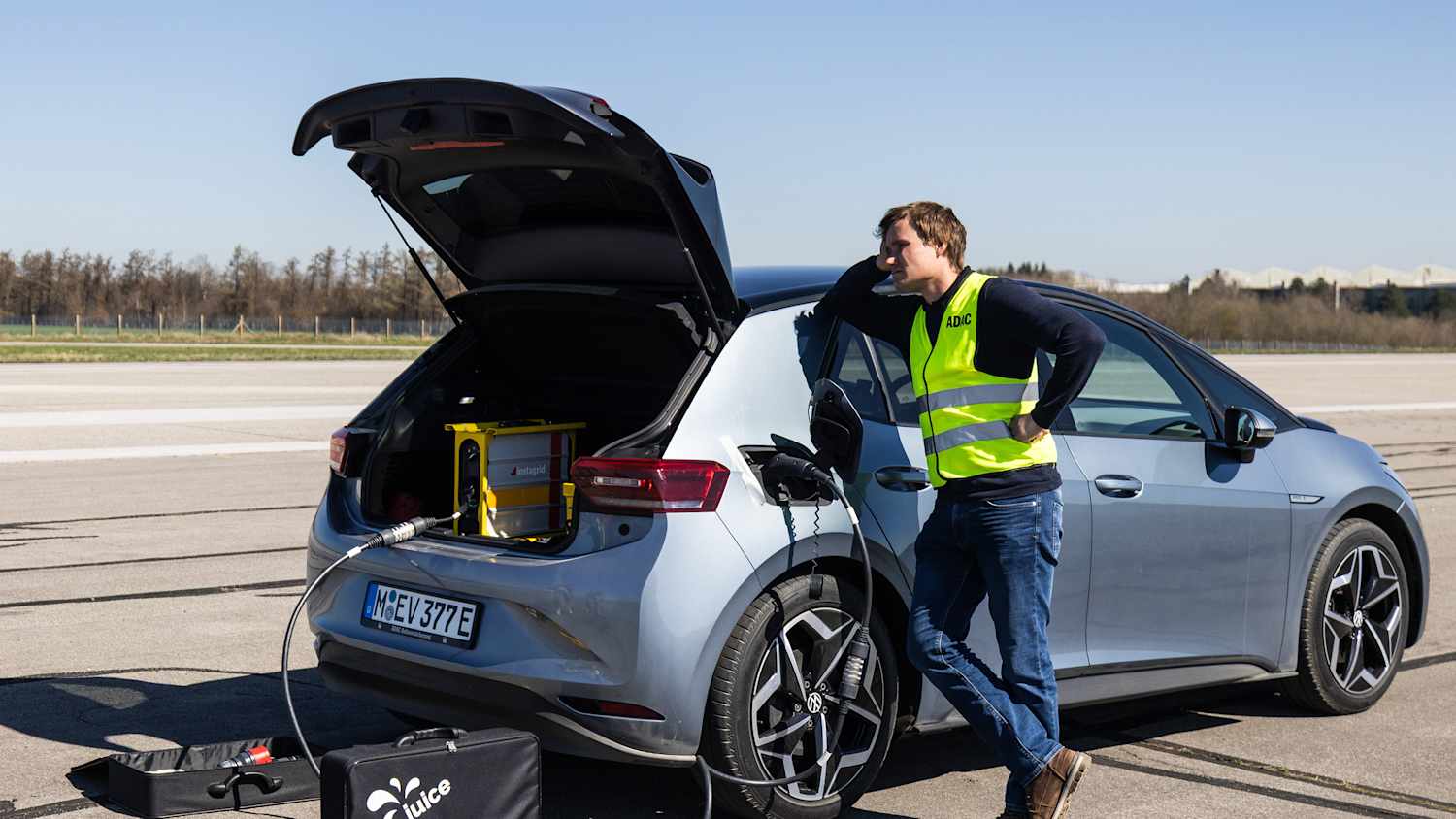 Ein Mann der an seinem Auto steht und wartet bis es ein wenig geladen hat um weiterfahren zu können
