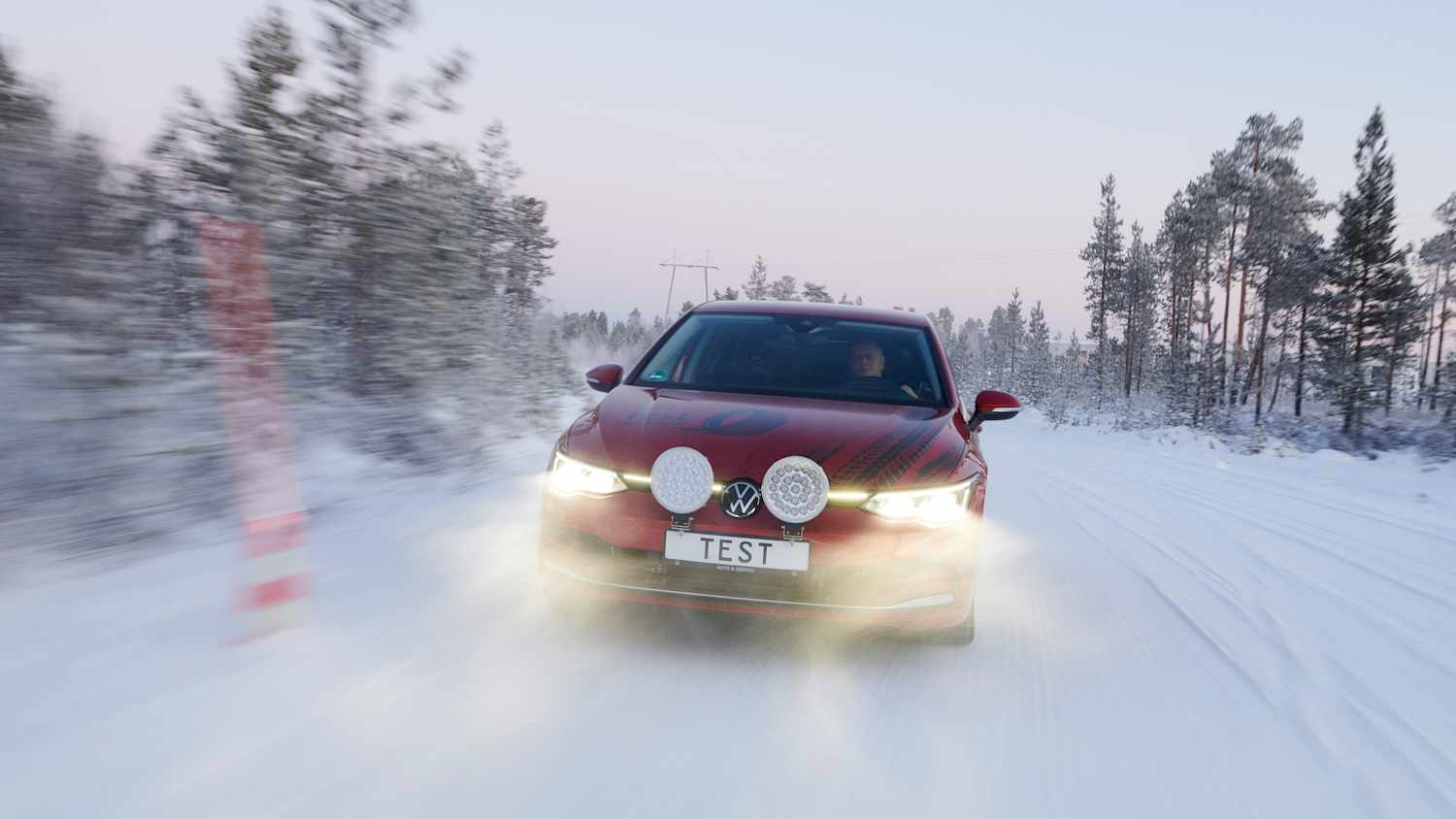 Ein Auto fährt auf einer zugeschneiten Strecke beim Winterreifentest in Finnland