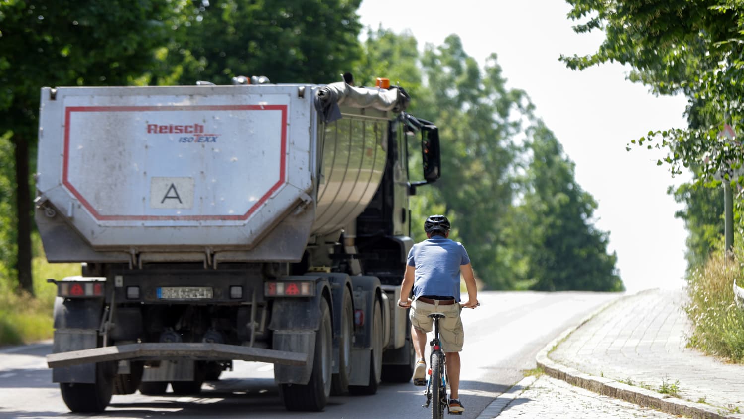 Ein LKW fährt mit geringem Abstand an einem Fahrradfahrer vorbei
