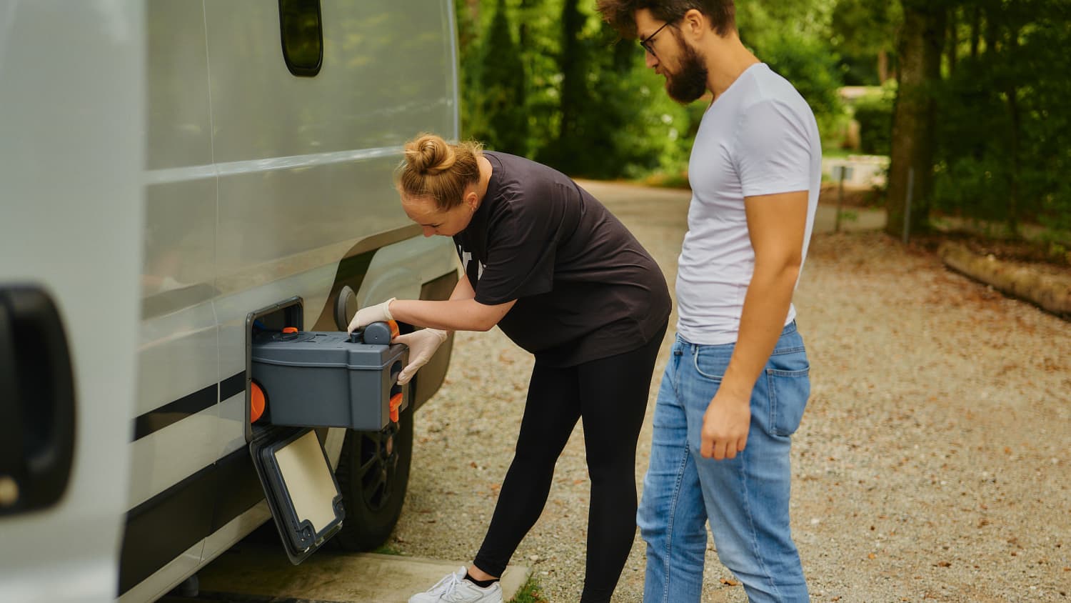 Eine junge Frau verstaut nach dem Leeren die Campingtoilette im Wohnmobil